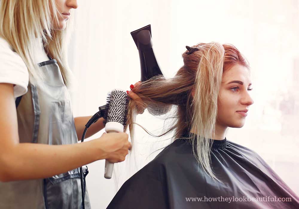 Hair styler drying hair of a woman